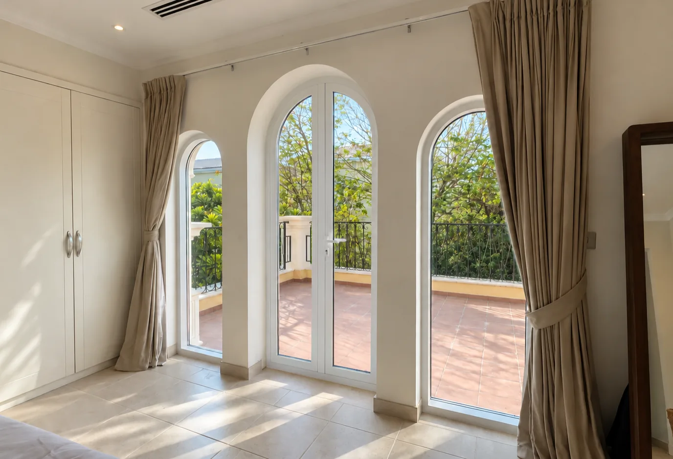 Arched white aluminium windows and a French door opening onto a villa balcony in Dubai